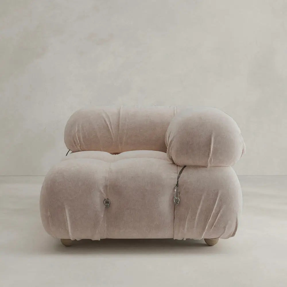The Belmont Sofa Left Armrest features plush, marshmallow-like curves, soft upholstery, pillow-inspired design, visible straps or fasteners, and a rounded shape—an iconic classic shown against a plain, neutral background.