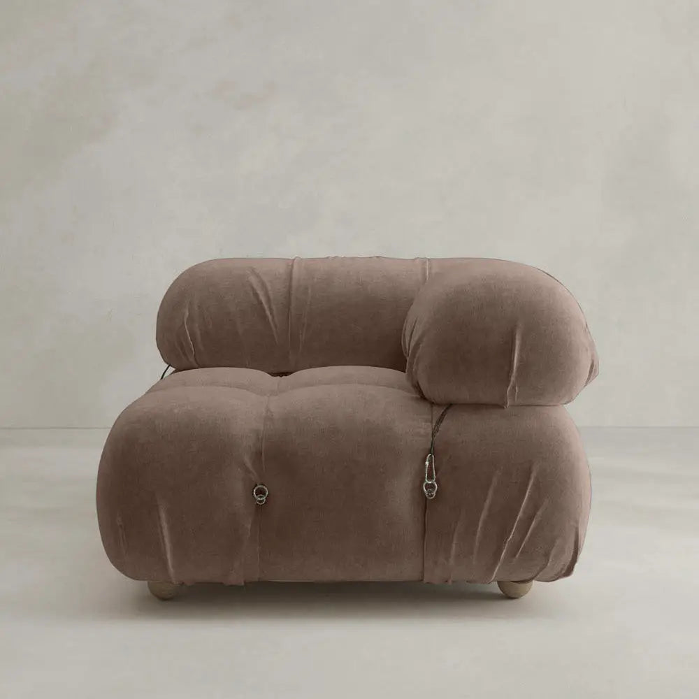 The Belmont Sofa Left Armrest features plush, brown upholstery with distinctive marshmallow-like curves and rounded, oversized cushions, set against a plain light gray wall and floor for a modern look.