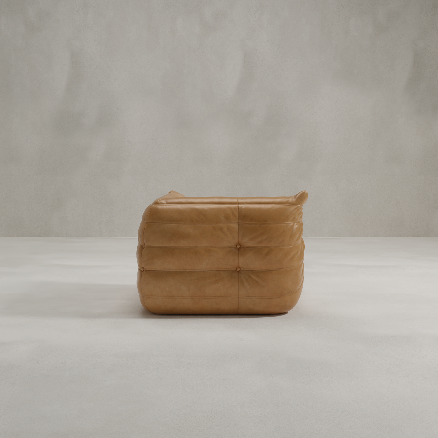 The Rolo Lounge Corner Sofa in tan leather, featuring a tufted, padded design inspired by mid-century style, is shown side-on atop a light gray floor against a plain textured light gray wall.