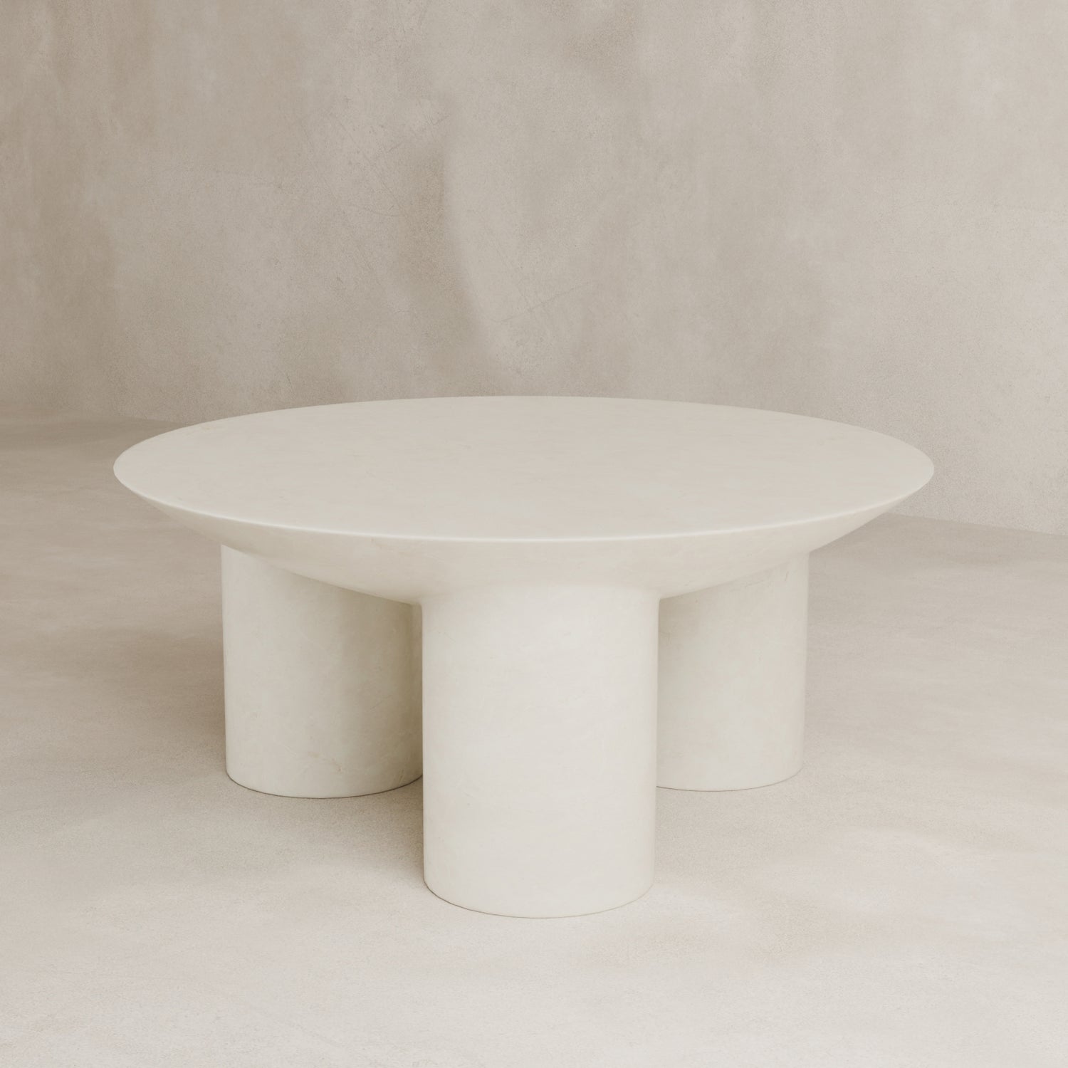 The Luna Coffee Table features a modern, minimalist round fiberglass design with a smooth surface and three thick tubular legs, displayed against a neutral-toned background.