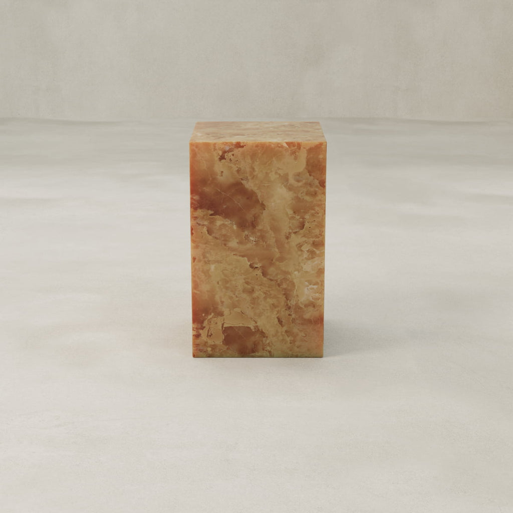 The Ambeline Onyx Plinth - Tall is a rectangular brown and beige marble piece with rust-toned marbling, adding organic elegance as it sits on a smooth, light-colored surface against a neutral backdrop.