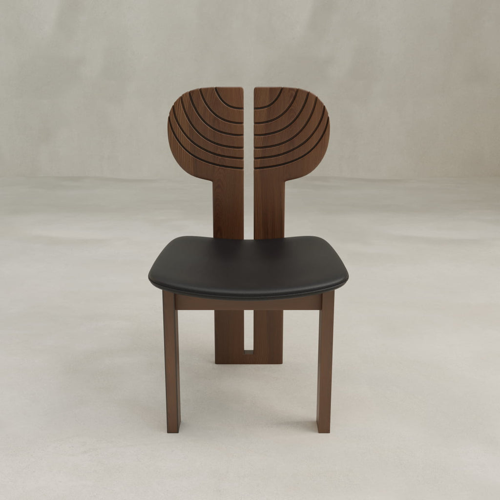 The Arnaud Dining Chair features a modern wooden frame with a black seat and artistic curved carved lines on the backrest, making it ideal for enhancing any dining area in a light, minimalist setting.