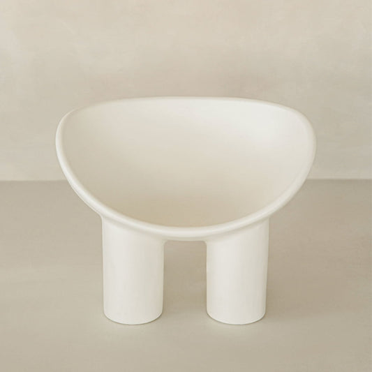 The Arrio Chair features a modern, minimalist design with a rounded seat and two thick cylindrical legs, set against a neutral beige background for an avant-garde touch.