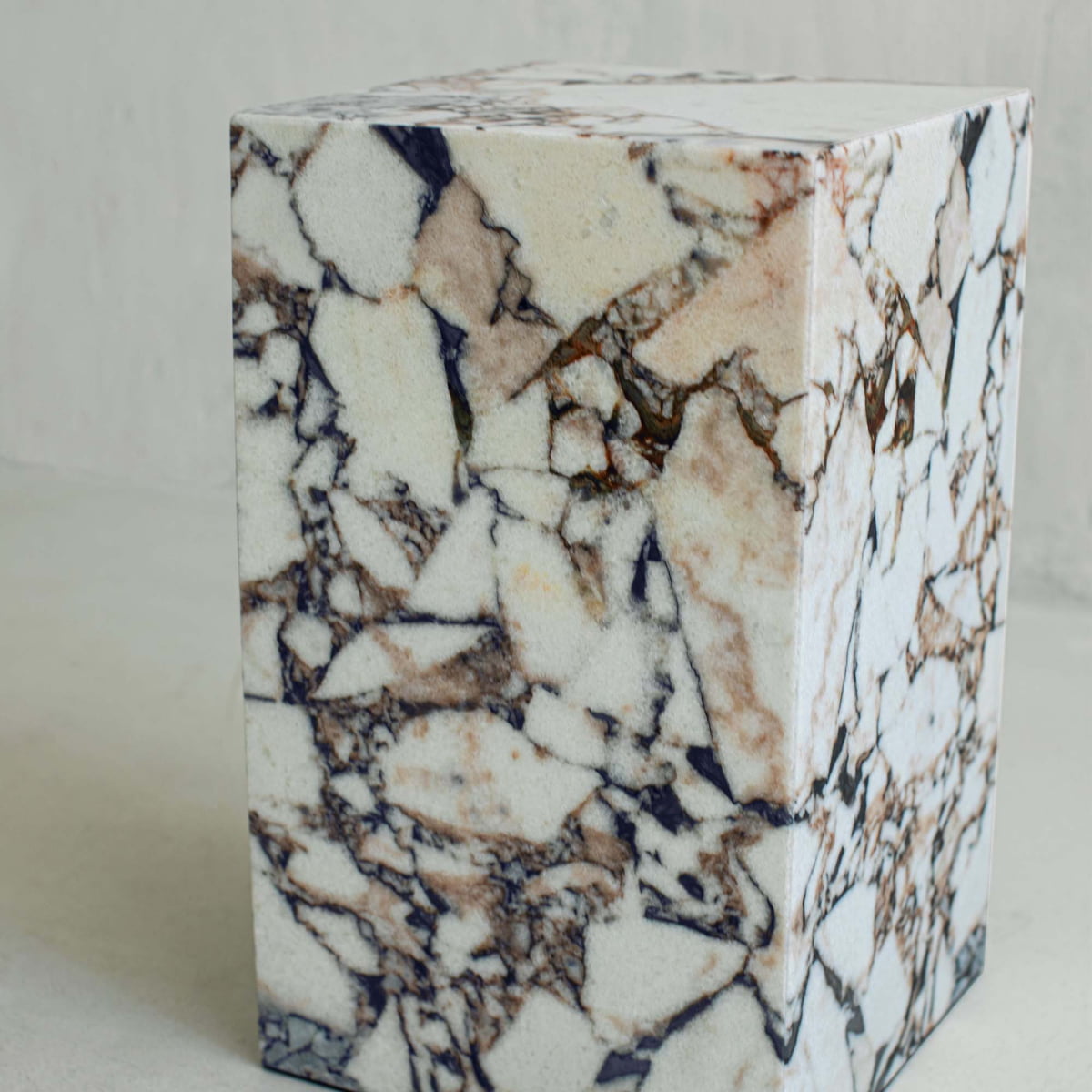 The Turkish Calacatta Plinth Tall features a polished, tall profile with a striking white, brown, and black veined marble pattern, set against a light background for an elegant look.