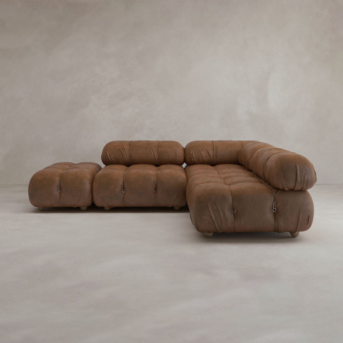 The Belmont Sofa Combination B is a modern, brown, tufted modular sofa with rounded edges and a matching ottoman, shown against a plain light gray background.