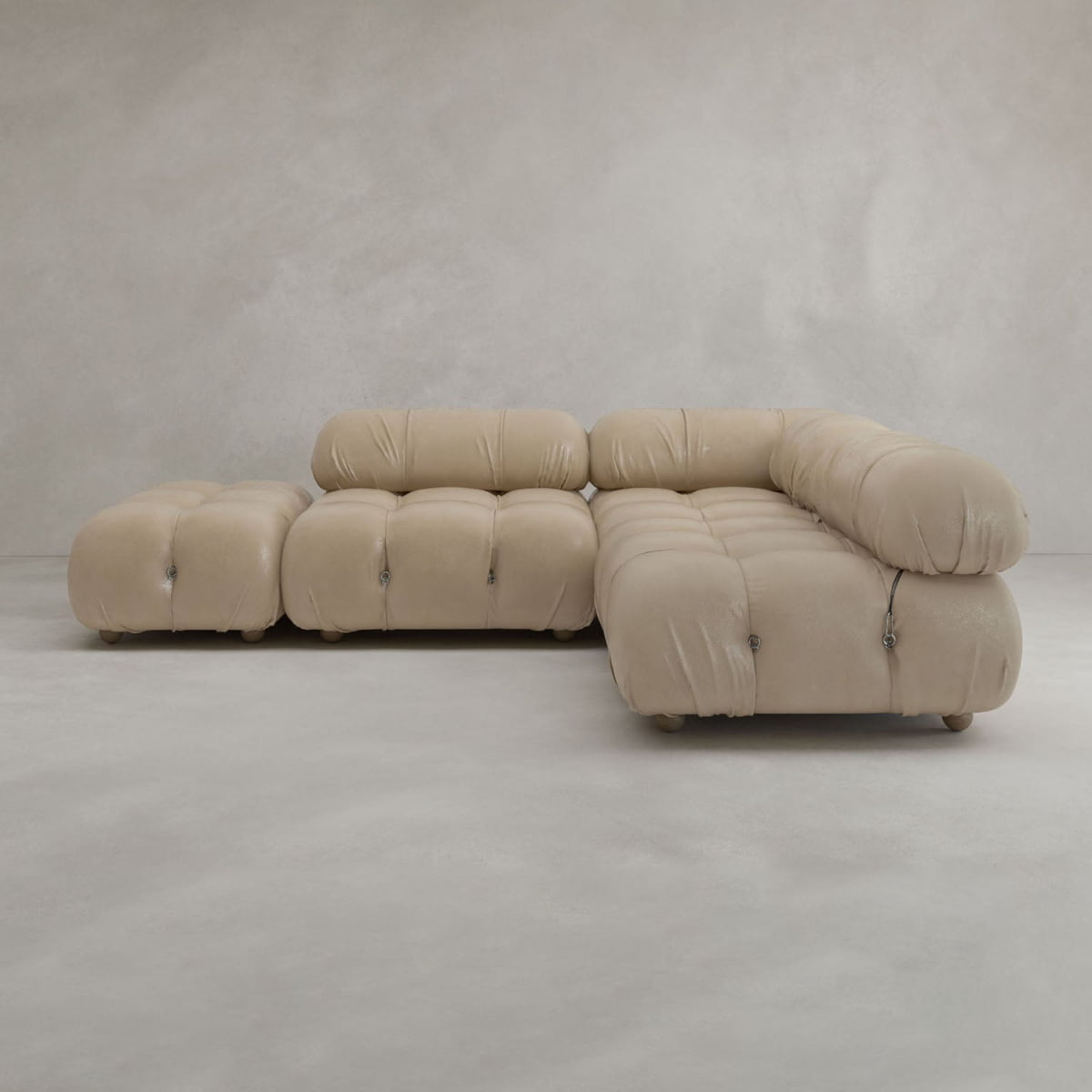 The Belmont Sofa Combination B features a modern beige modular design with tufted, rounded cushions, displayed against a plain light gray wall and floor.
