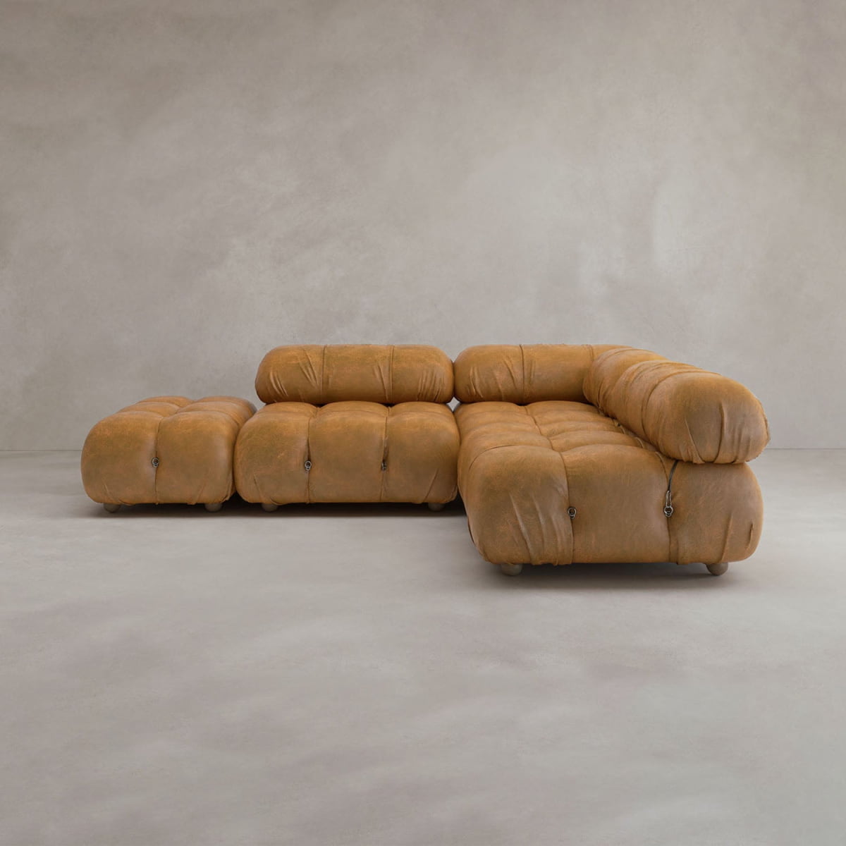 The Belmont Sofa Combination B, a modular tan leather cloud sofa with plush, rounded cushions, sits against a plain light gray background. Its contemporary and minimalist design is showcased with no other objects present.