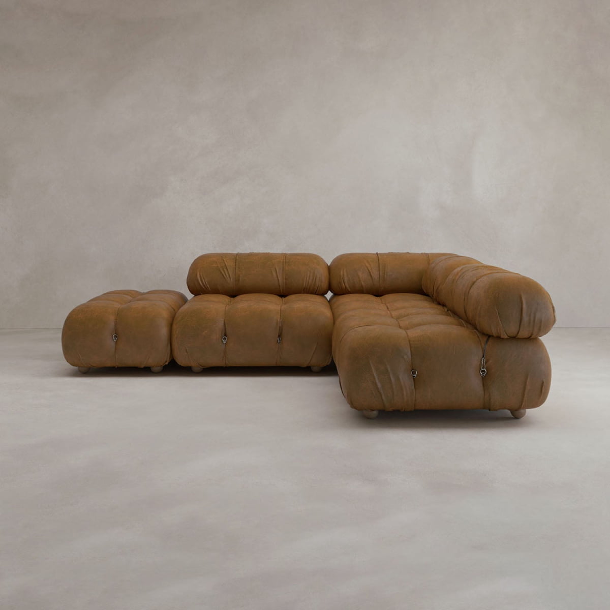 The Belmont Sofa Combination B is a modular brown leather sectional with rounded tufted cushions and a matching ottoman, inspired by the classic cloud sofa, shown against a plain light wall and floor.