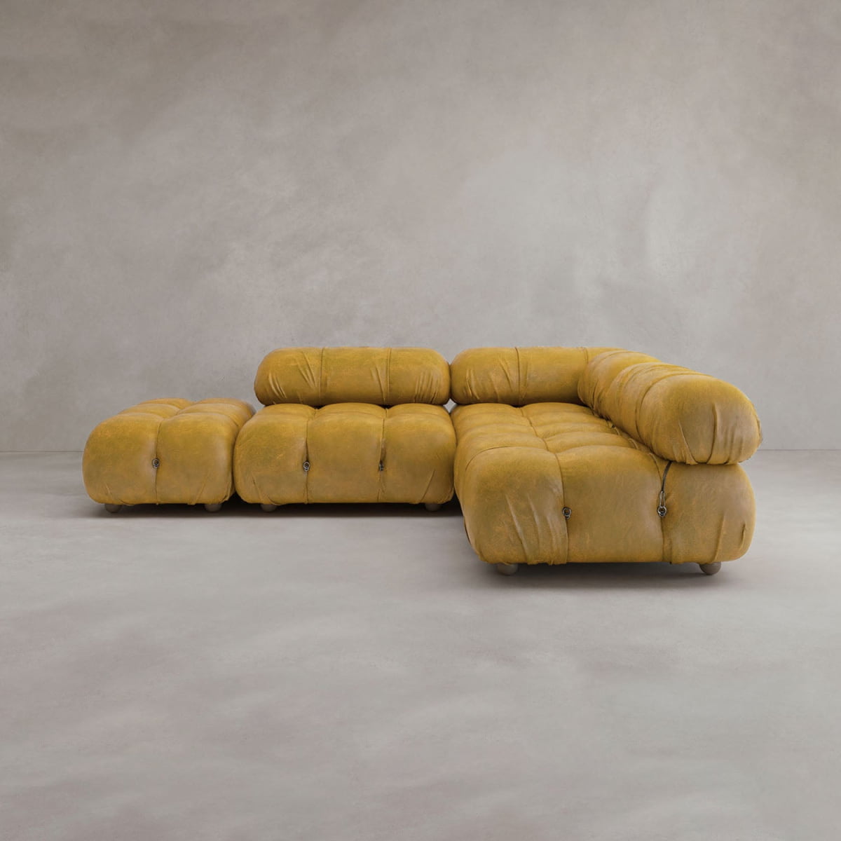The Belmont Sofa Combination B in mustard yellow features a modular, tufted, plush design and rounded cushioned edges for comfort. This L-shaped cloud sofa stands out against a light gray wall and floor for a classic look.