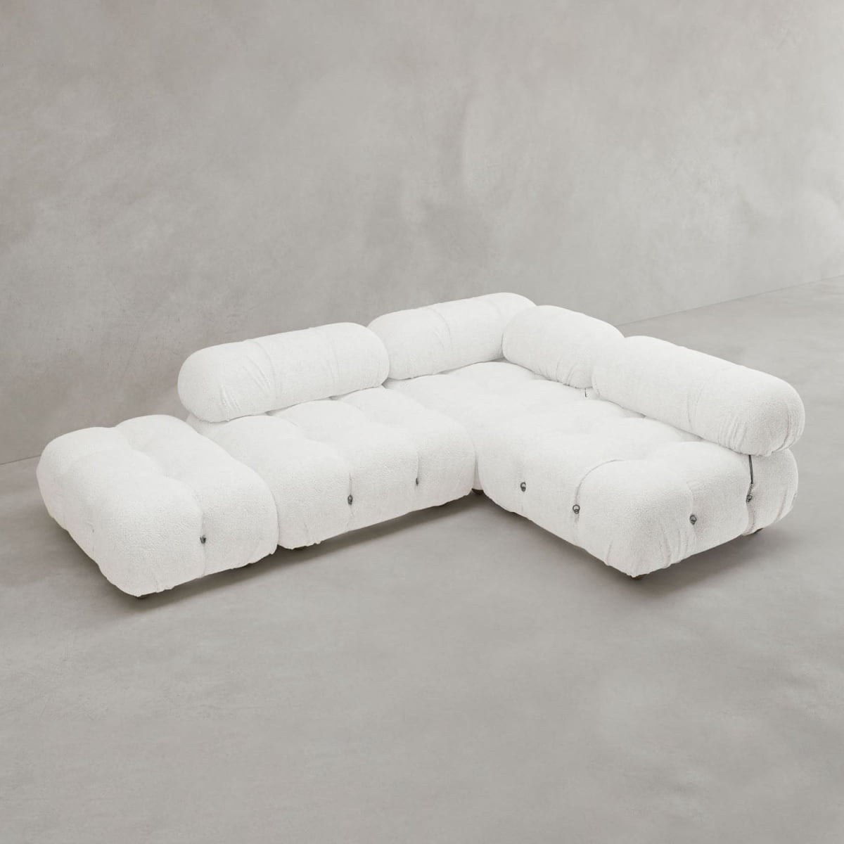 The Belmont Sofa Combination B is a modern, modular white sectional with plush tufted design and cylindrical backrests, showcased against a light grey minimalist background.