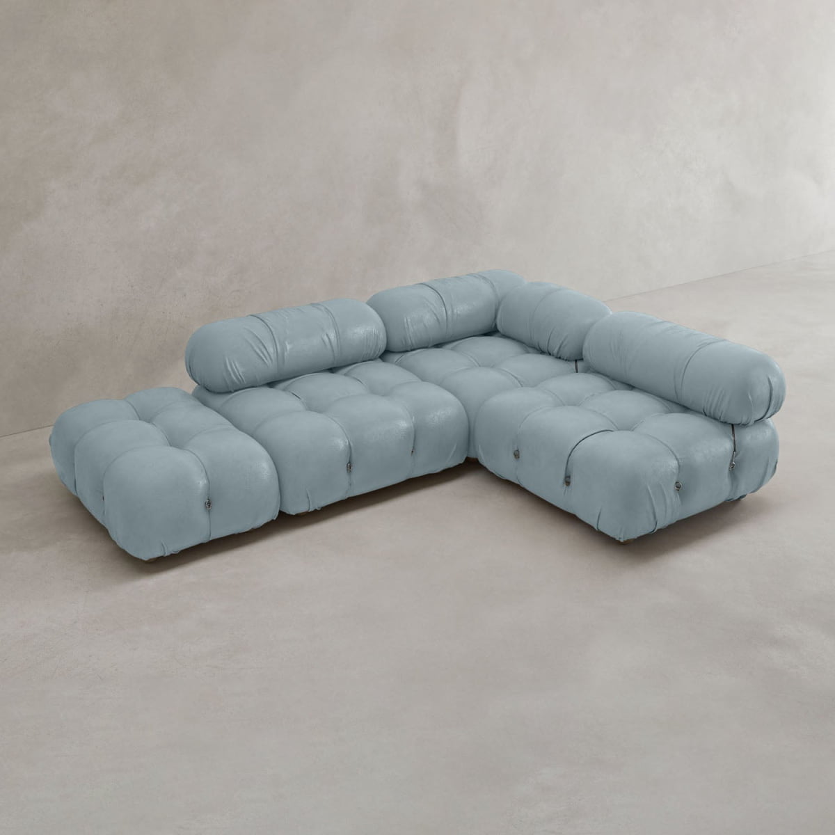 The Belmont Sofa Combination B is a modern, light blue modular sofa with tufted cushions, an L-shape design, low seat backs, and wide seats. Its style recalls the iconic cloud sofa, set against a light, minimalistic background.