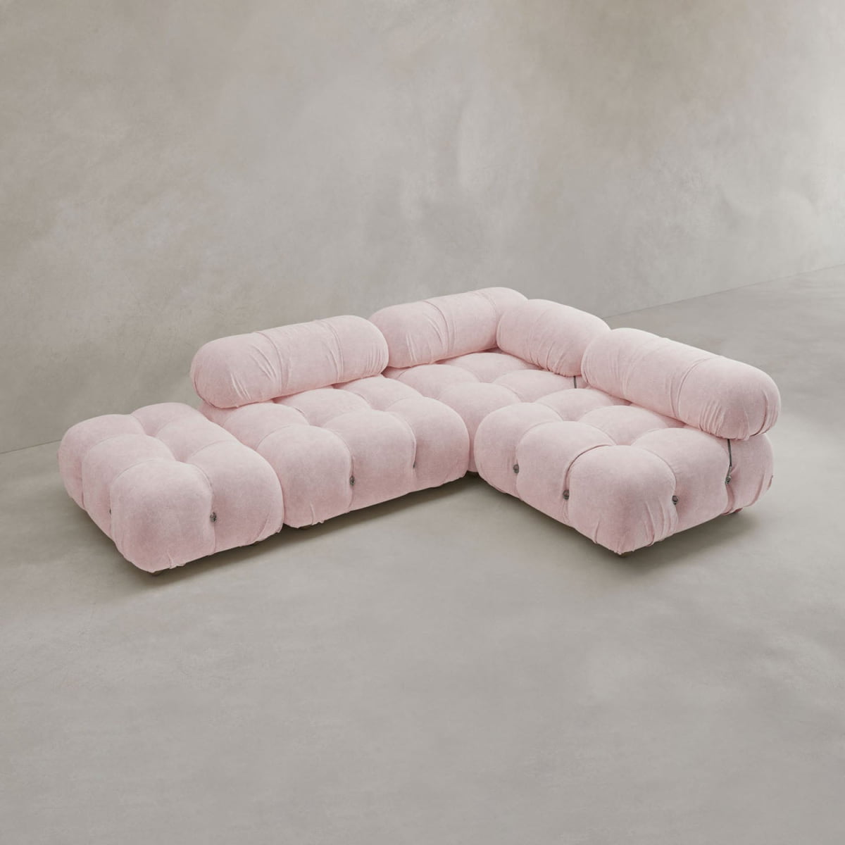 The Belmont Sofa Combination B, a modern modular cloud sofa with tufted light pink upholstery, sits on a smooth light gray floor against a minimalist neutral wall.