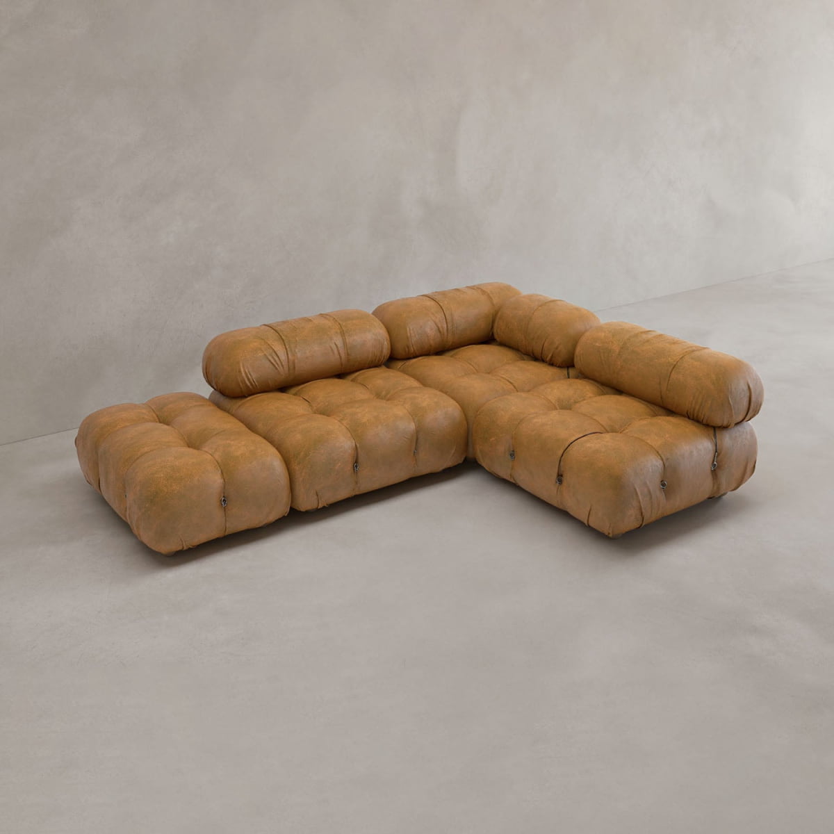 The Belmont Sofa Combination B, a brown tufted modular sofa with plush rounded cushions and a low profile, sits on a light gray floor against a plain light-colored wall.