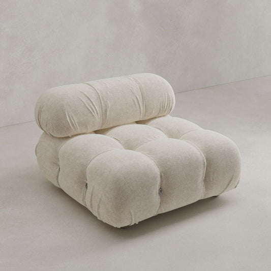 The Belmont Sofa Middle Module Rental features plush, tufted cream upholstery with a rounded backrest, offering modern comfort and iconic style against a light, neutral backdrop.