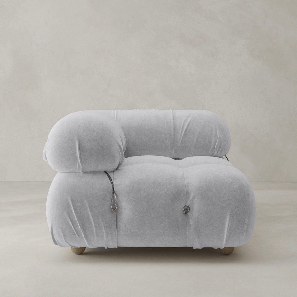 The Belmont Sofa Right Armrest, with plush light gray cushions and leather strap accents, adds an iconic classic touch to your layout, set against a minimalist beige backdrop.