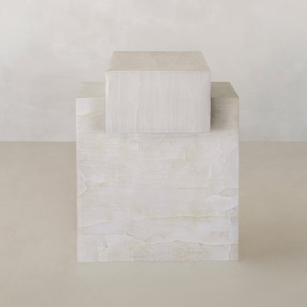 The Bianca Short is a minimalist sculpture featuring two stacked rectangular blocks, the smaller atop a larger White Onyx Plinth, both with a smooth light beige texture and natural luminosity set against a neutral background.