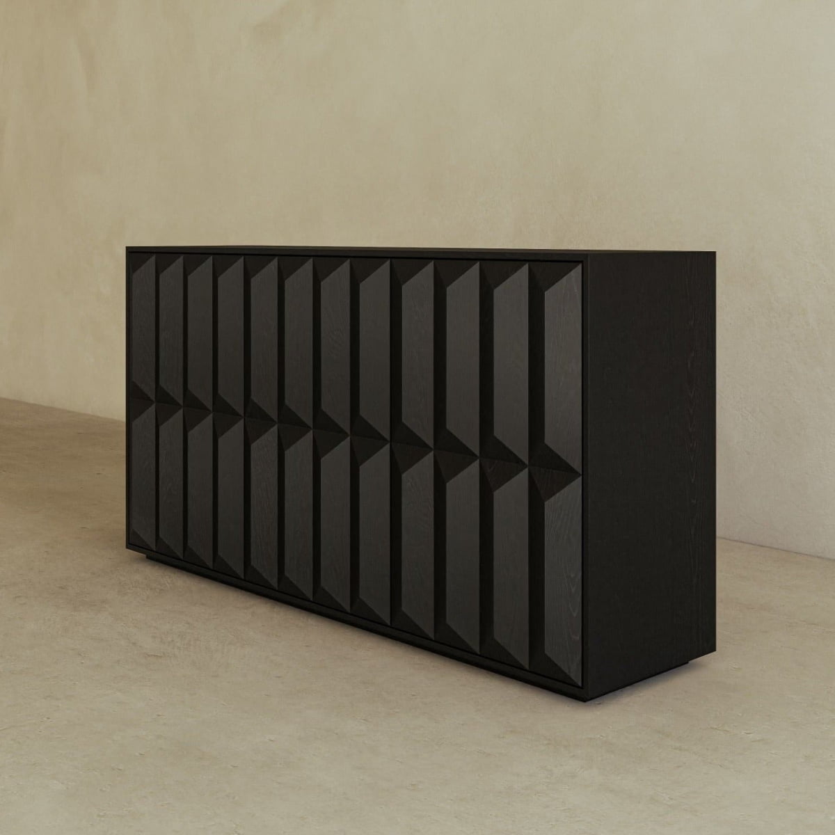 The Braemar Console Large by Anthony Newman features a modern black design with a geometric, textured front panel. It stands against a beige wall on a light, smooth floor.