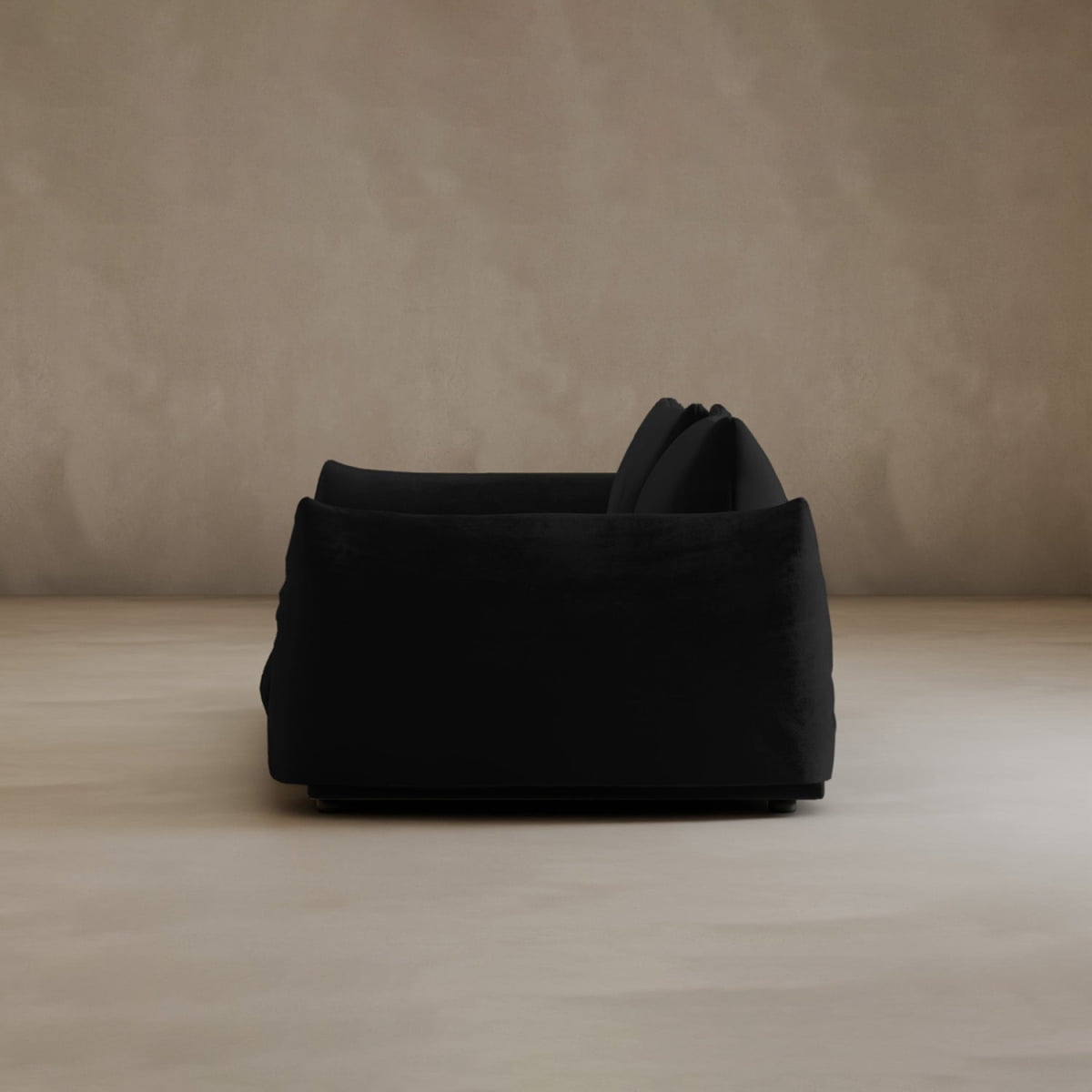 A black, modern Calypso Loveseat with two cushions is displayed in profile against a neutral beige background in a minimal, empty room, radiating contemporary elegance.
