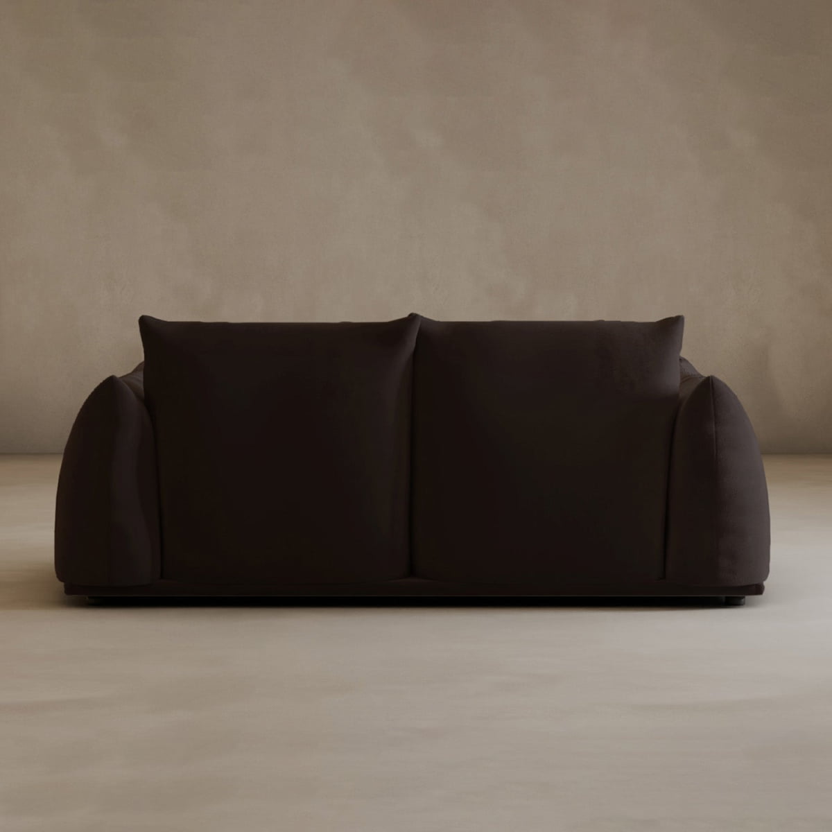 A modern, minimalist Calypso Loveseat in dark brown with soft, rounded edges and two large back cushions exudes modern elegance against a plain, light beige wall and floor.