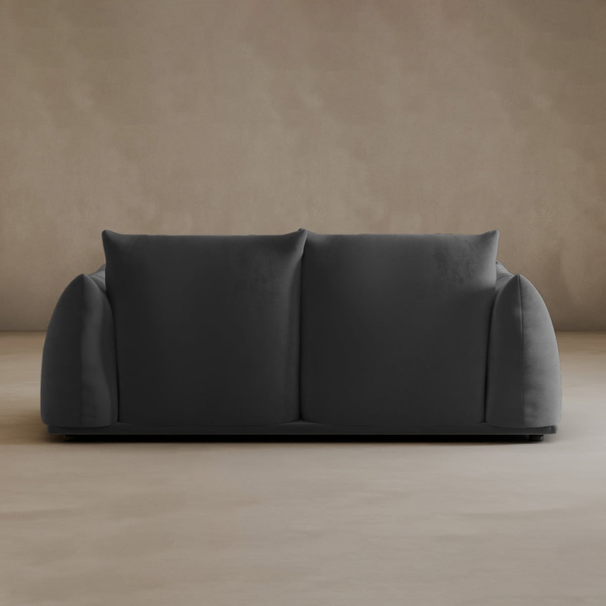 The Calypso Loveseat in dark gray showcases minimalist design and modern elegance with two large seat cushions and a low back, placed against a plain beige wall and smooth floor.
