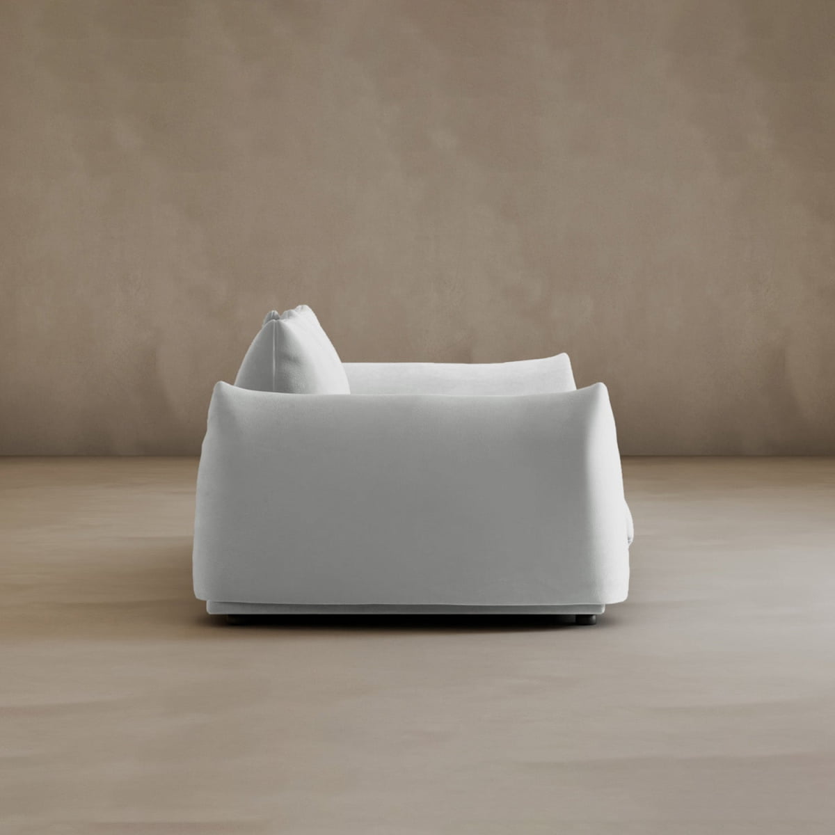 The Calypso Loveseat, featuring modern elegance and plush cushions, is displayed from the side against a sleek beige wall and floor, highlighting a minimalist and serene setting.