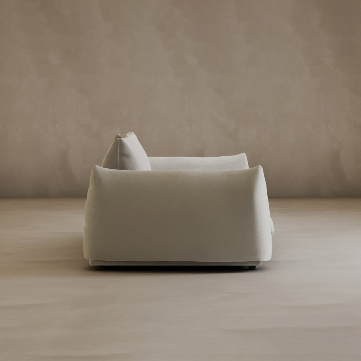 A minimalist, modern off-white Calypso Loveseat with plush cushions is shown from the side, exuding elegance in a neutral room with beige walls and floor.