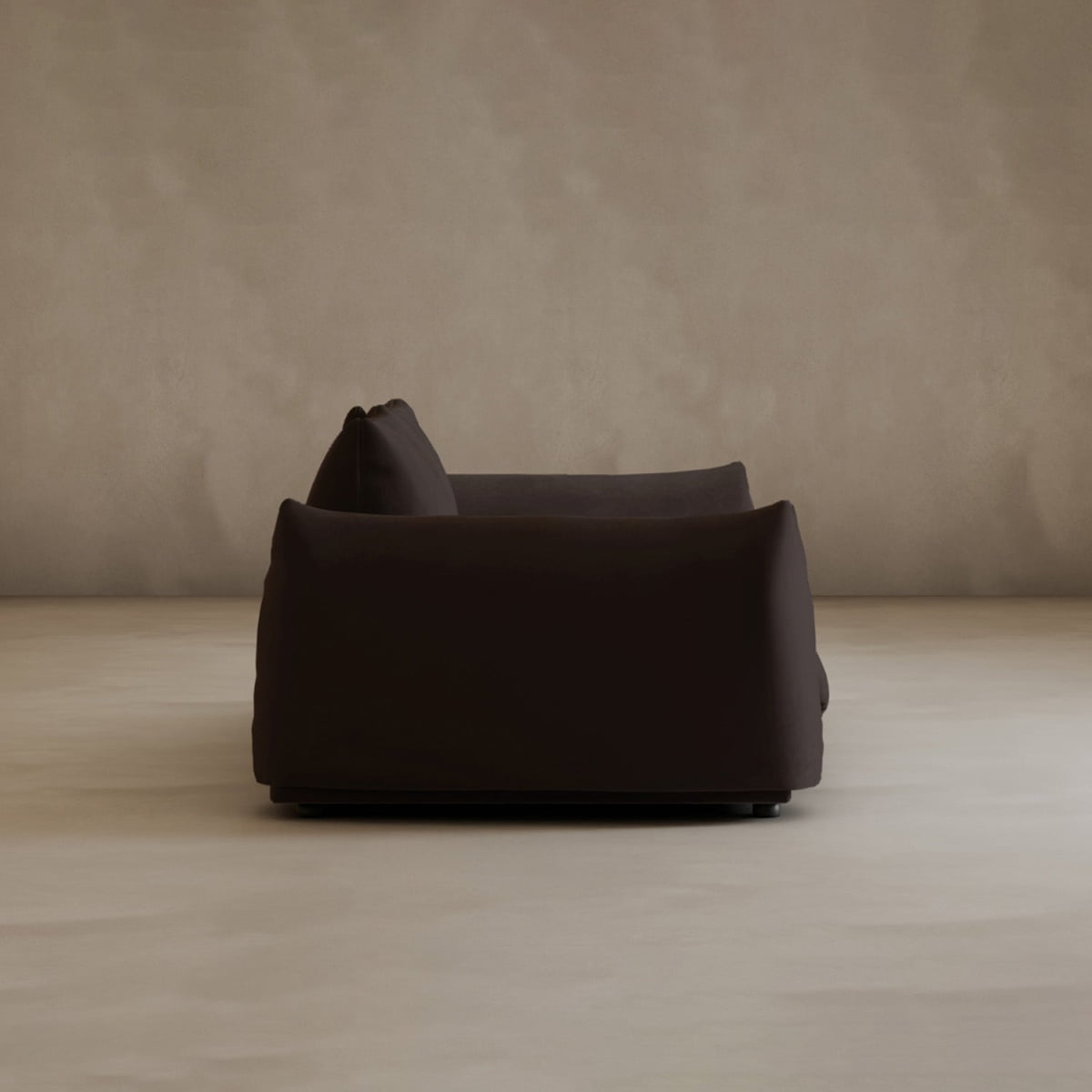 A Calypso Loveseat in dark brown, seen from the side, exudes modern elegance in a minimalistic room with beige walls and a light-colored floor.