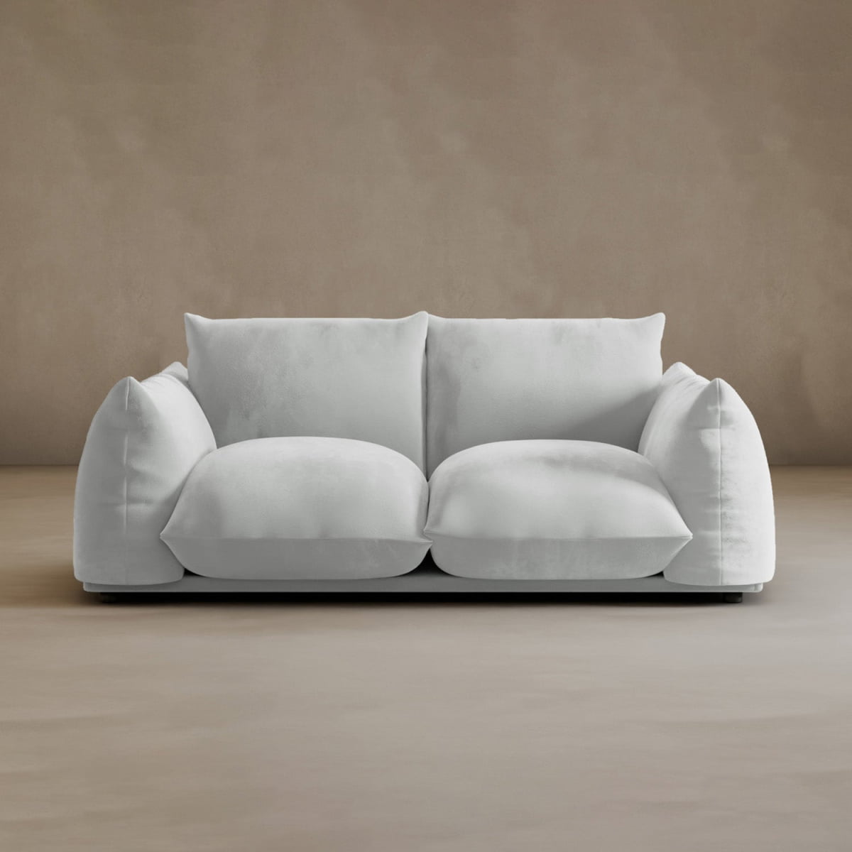 The Calypso Loveseat, a plush white 2-seater with oversized cushions, brings modern elegance to your space, shown here on a light beige floor with a matching beige wall background.