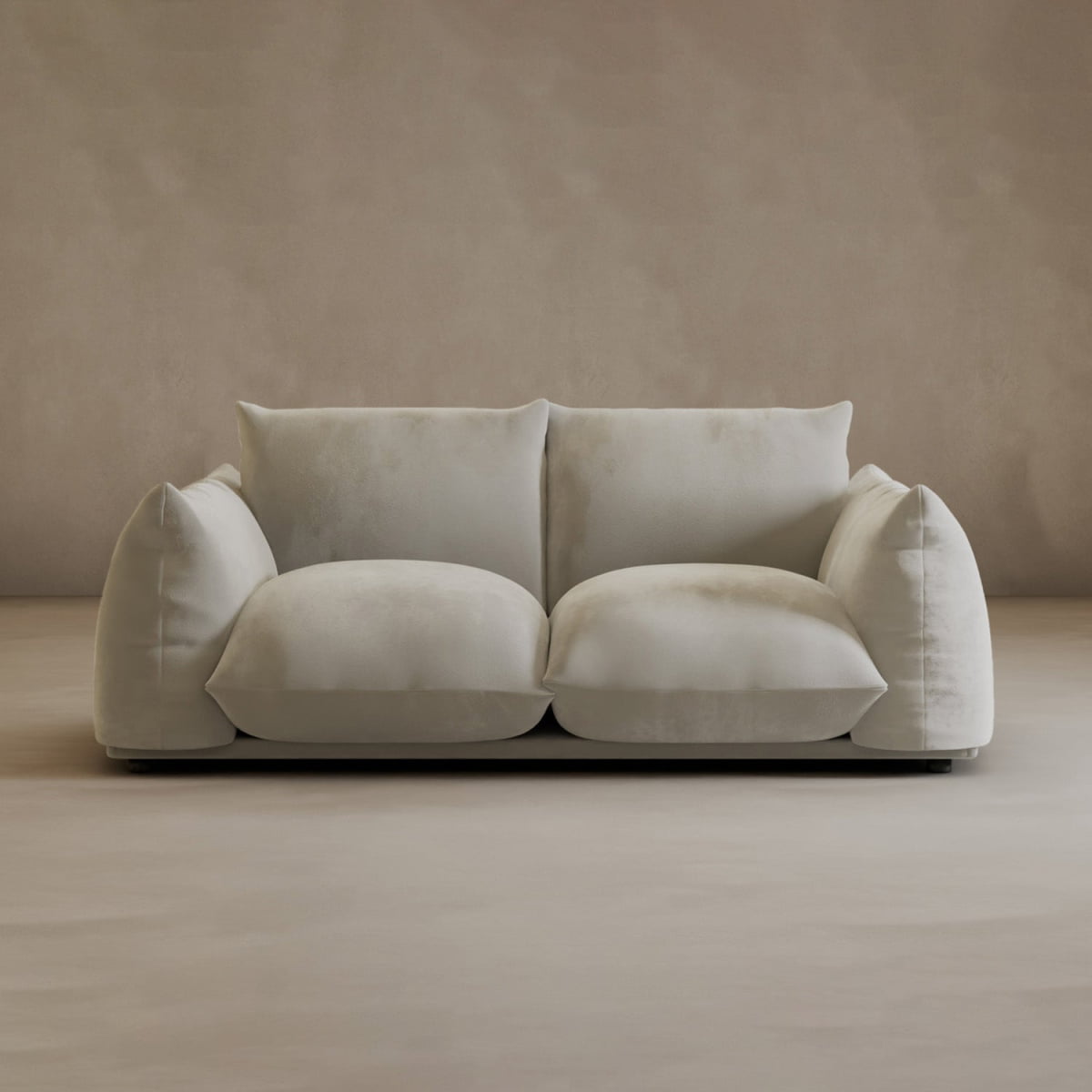 A modern, plush Calypso Loveseat with overstuffed cushions sits against a matching beige wall and floor, infusing modern elegance into this minimal, neutral-toned room.