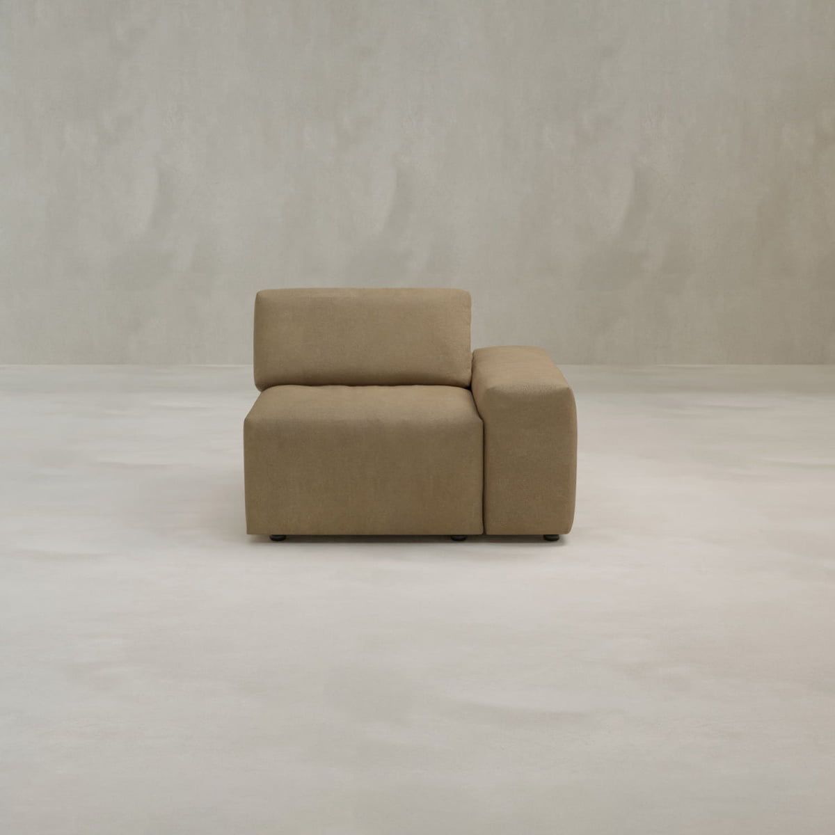 The Canonbury Left Armrest, a modern beige armchair in high-performance fabric, sits on a light, smooth floor against a plain, textured off-white wall.