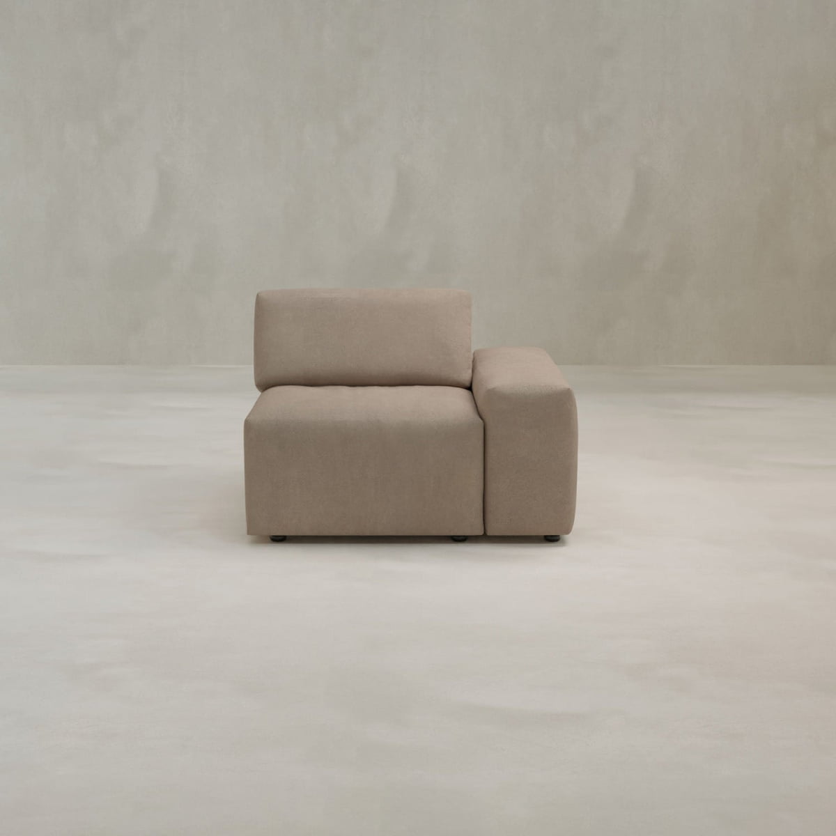 The Canonbury Left Armrest is a modern, minimalist beige armchair in high-performance fabric, featuring a left-side armrest, set on a light seamless floor against a plain textured off-white wall.