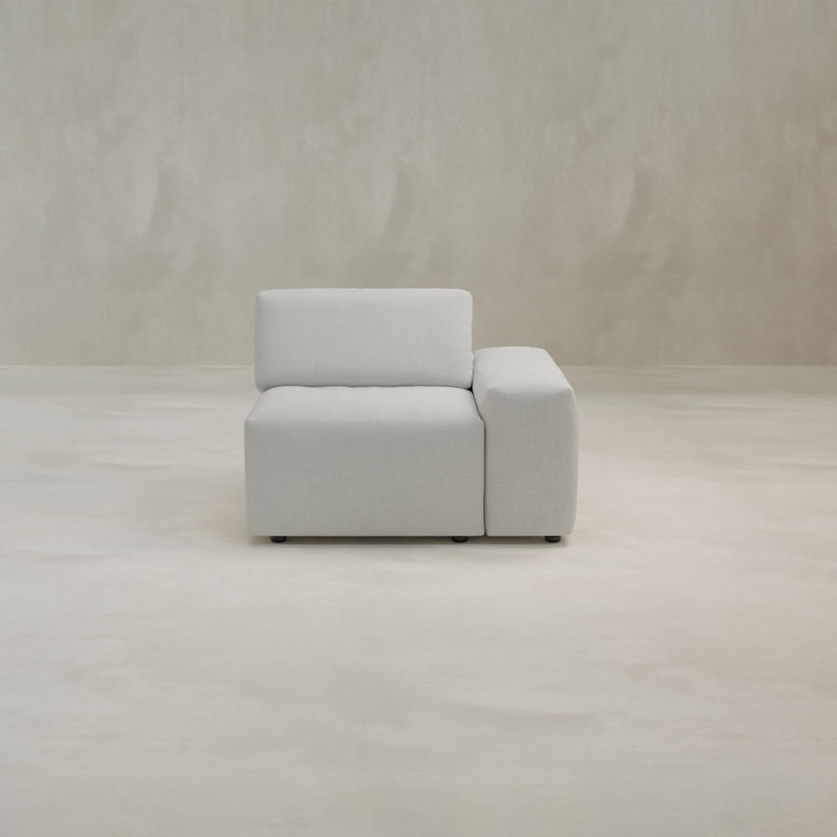 The Canonbury Left Armrest is a modern, light gray upholstered chair with high-performance fabric, thick seat and backrest, offering contemporary comfort on a seamless beige floor against a neutral textured wall.