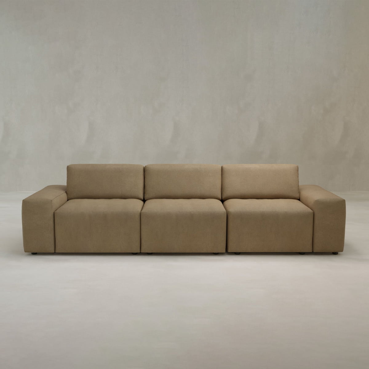 The Canonbury Three Seater Sofa is a modern, minimalist beige sectional with wide seats and low armrests, crafted in high-performance fabric for contemporary comfort and shown against a plain, light background.
