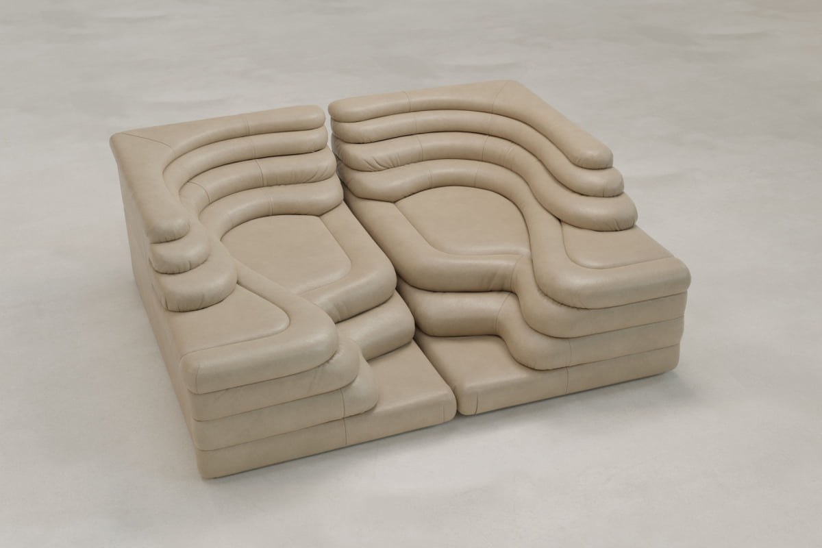 The Cascata 2 Piece Sofa features connected, modular beige seating with layered, curved contours resembling sculpted terraces, offering a modern look against a light floor.