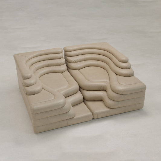 The Cascata 2 Piece Sofa Rental is a modular tan leather sofa with a sculptural design featuring curved, stepped sections that create an abstract, organic shape—making it a striking modern centerpiece on any light floor.