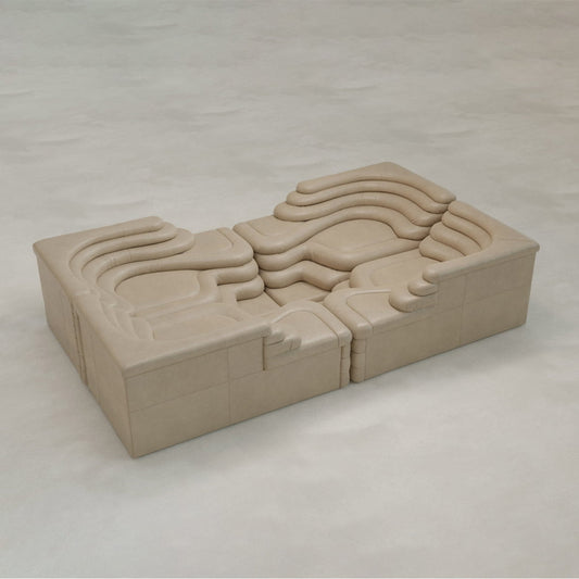 The Cascata 4 Piece Sofa Rental features sculpted, wave-like cushions and a modular beige design, adding luxurious style to any light, neutral floor.