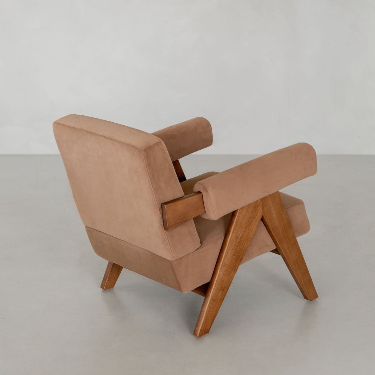 The Chelsea Lounge Chair features light brown faux mohair upholstery and angled wooden legs in a mid-century modern design, shown from a rear side angle against a plain light gray background to highlight its style.