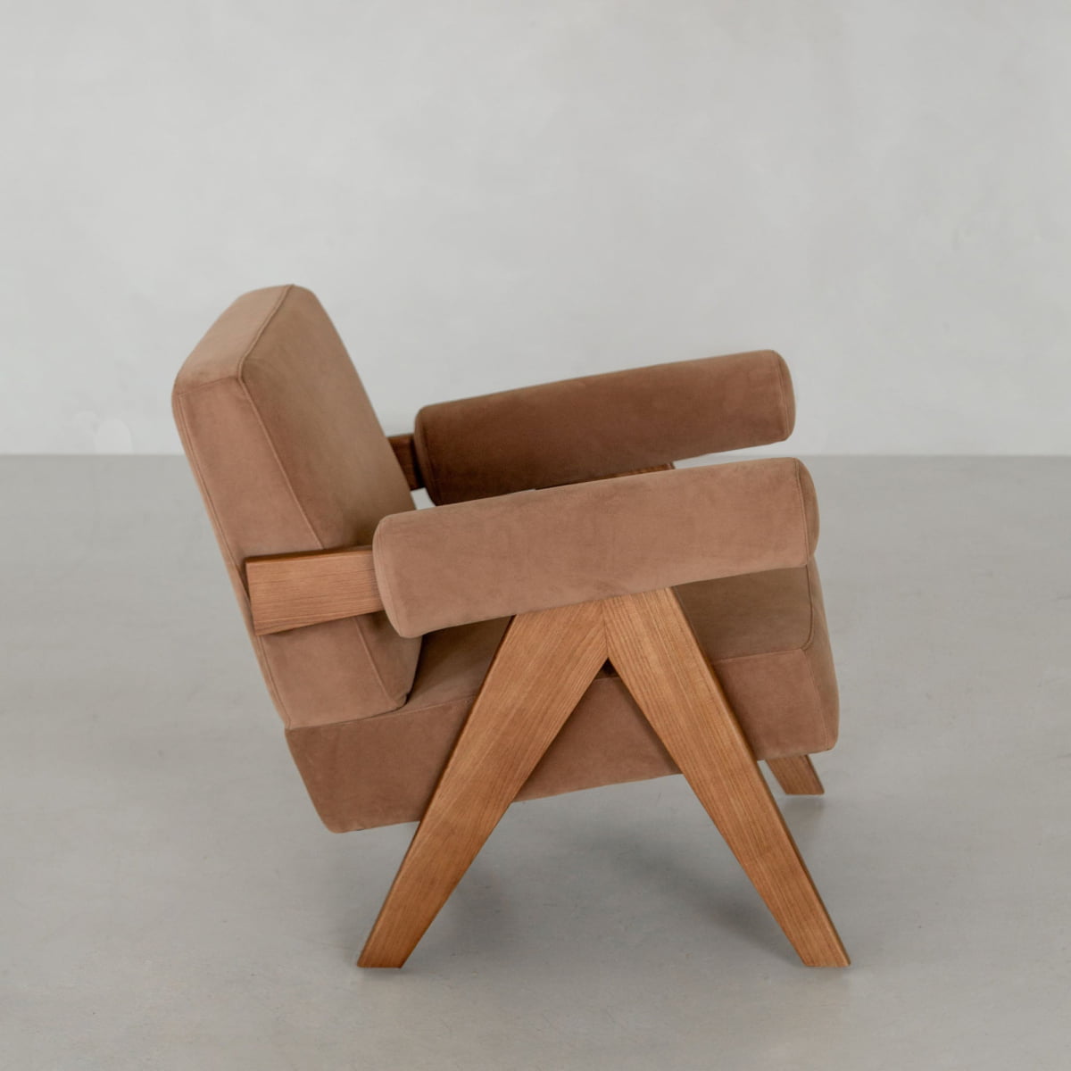 The Chelsea Lounge Chair features tan faux mohair upholstery and angled wooden legs, showcased in profile against a light gray background, offering a refined mid-century style.
