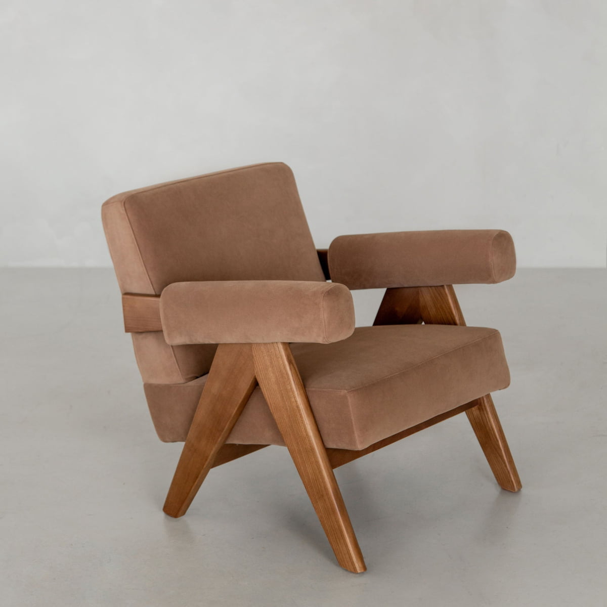The Chelsea Lounge Chair features light brown faux mohair cushions and a wooden frame, showcased on a plain light grey background for a refined mid-century look.