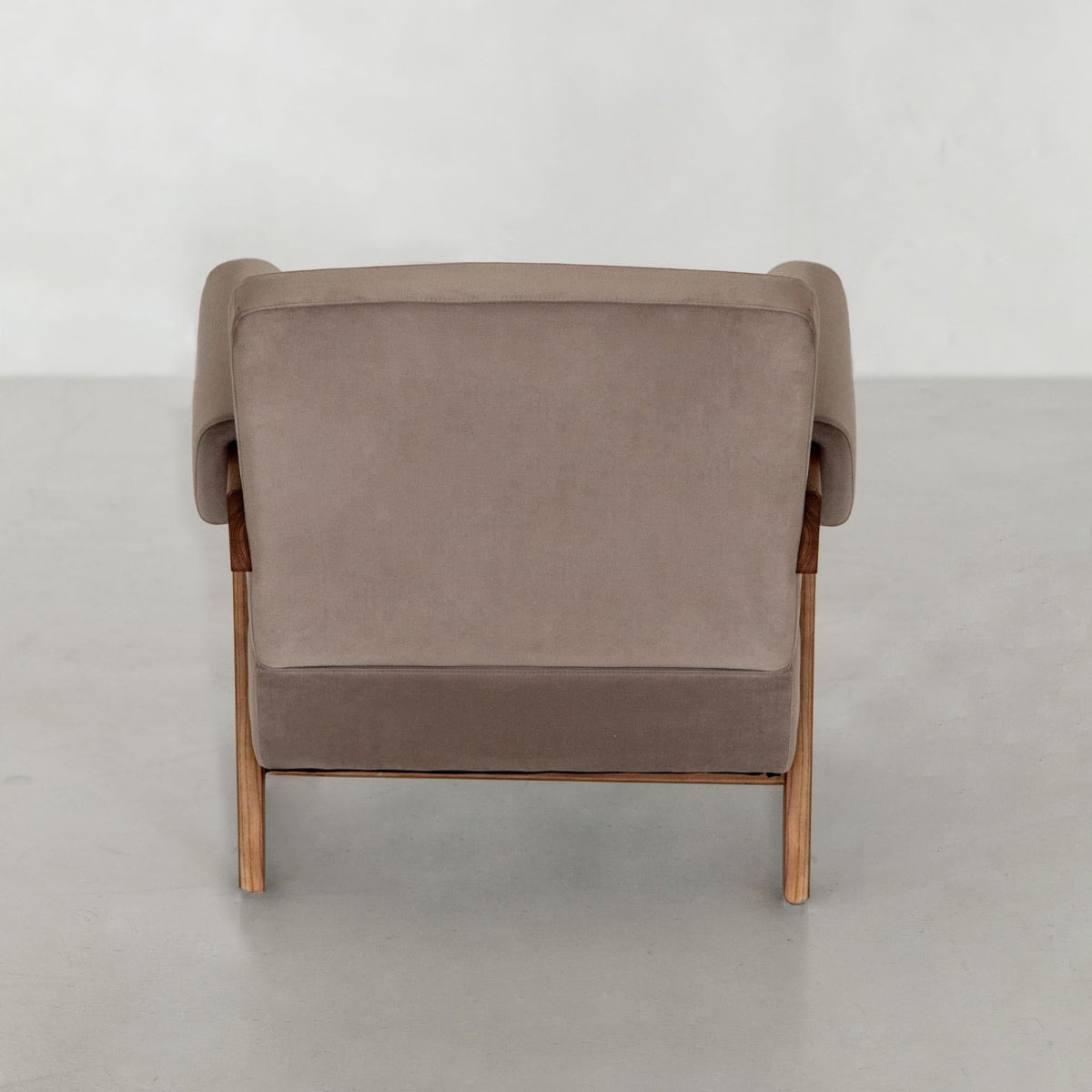 The Chelsea Lounge Chair features light brown faux mohair upholstery and wooden legs, shown from the back against a plain light gray background, highlighting its refined mid-century design.