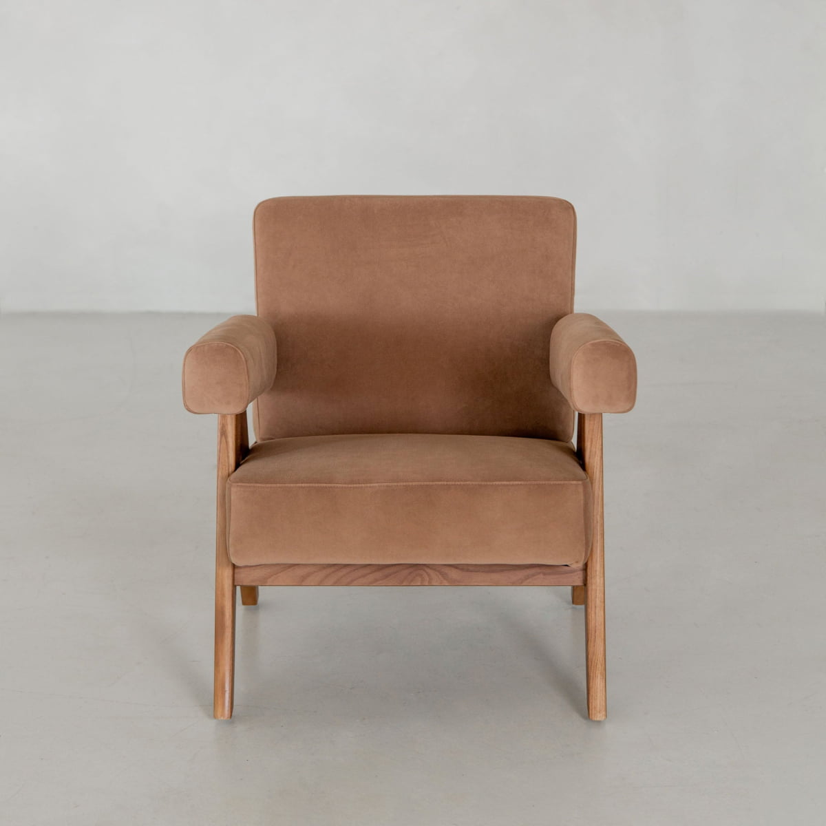 The Chelsea Lounge Chair, featuring a mid-century design with wooden legs and frame, is upholstered in soft brown faux mohair and sits on a light gray floor against a plain light wall.