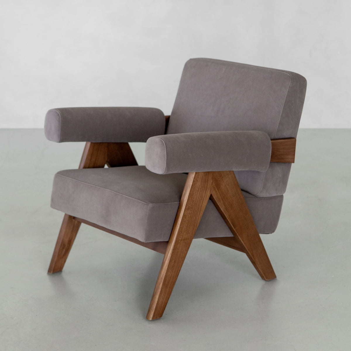 The Chelsea Lounge Chair features gray faux mohair, angled wooden legs, and arm supports for a refined mid-century look, shown against a plain light background.