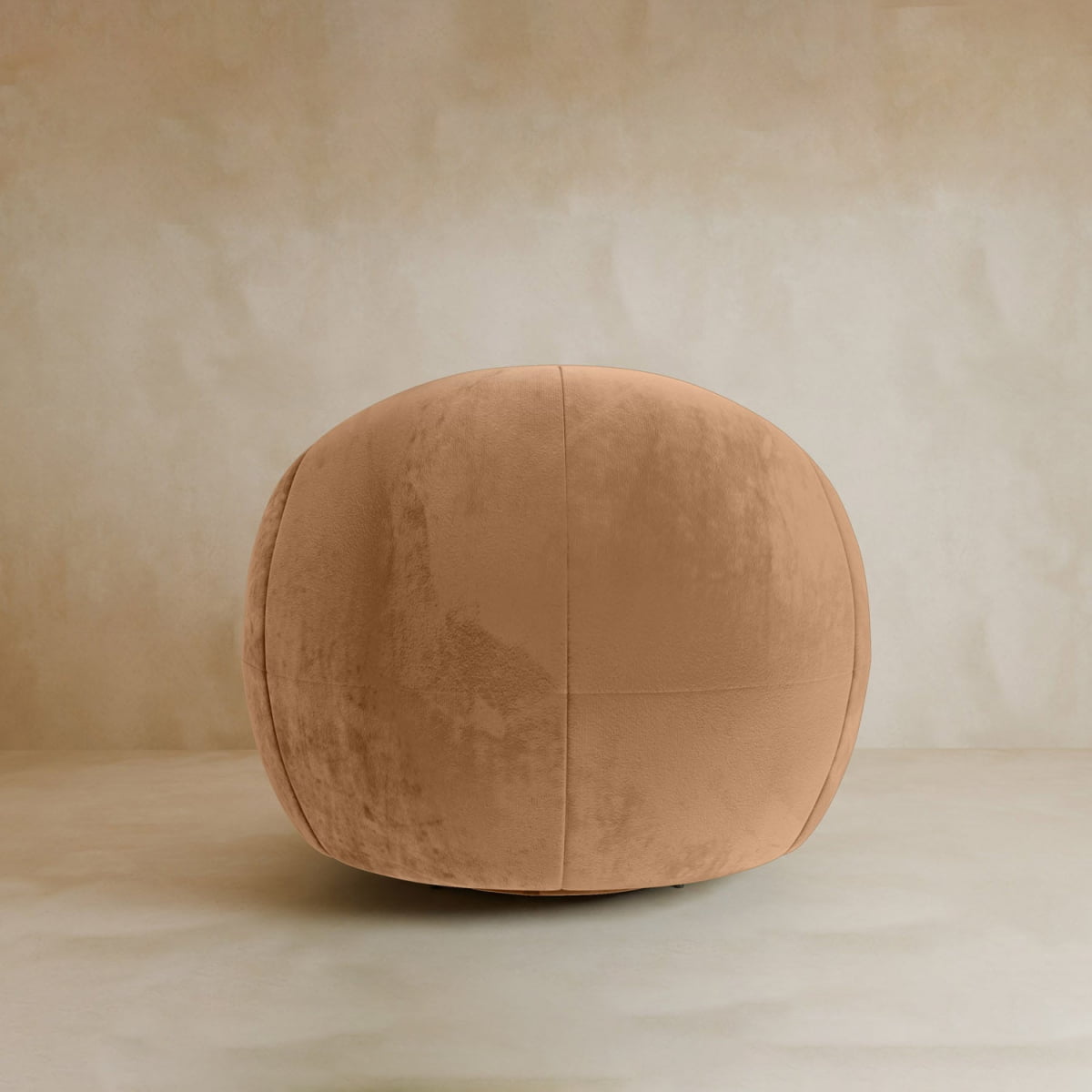 The Clara Armchair, featuring smooth velvet upholstery in soft light brown and subtle panel stitching, stands out against a neutral beige background with its large, minimalist contemporary design.