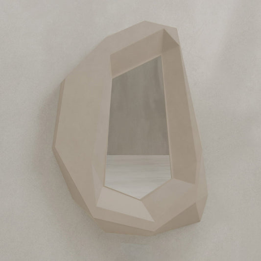 The Facet Mirror Small features an irregular, gemstone-inspired beige frame that adds modern sophistication and subtle brutalist style to any light-colored wall.