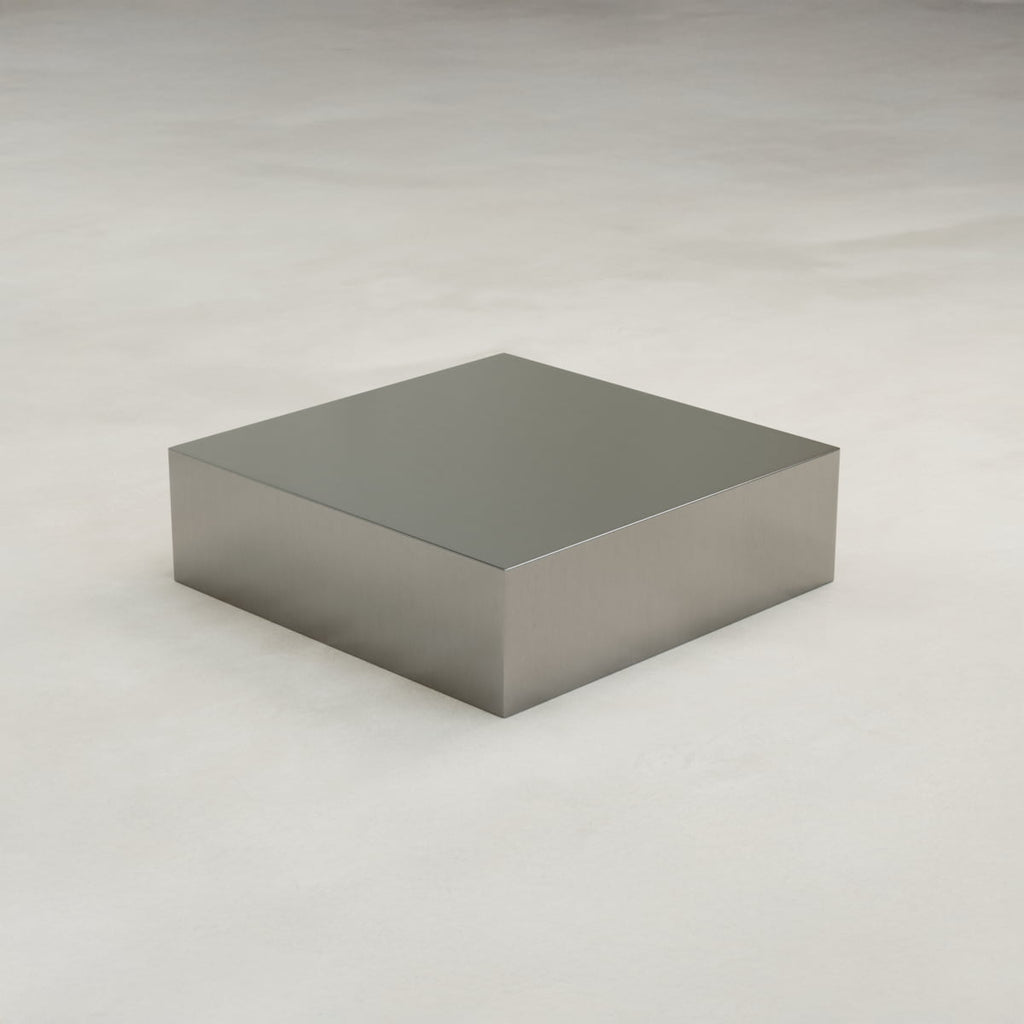 The Forge Steel Large Square Plinth features a shiny, metallic finish in rectangular form, displayed on a smooth, light surface against a neutral background for an industrial look.