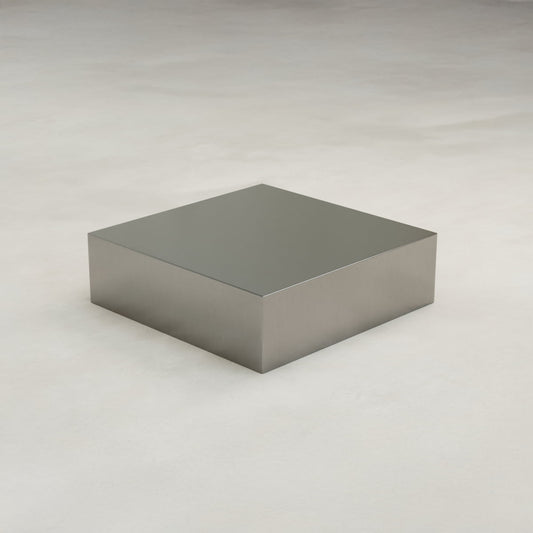 The Forge Steel Large Square Plinth features a shiny, metallic finish in rectangular form, displayed on a smooth, light surface against a neutral background for an industrial look.
