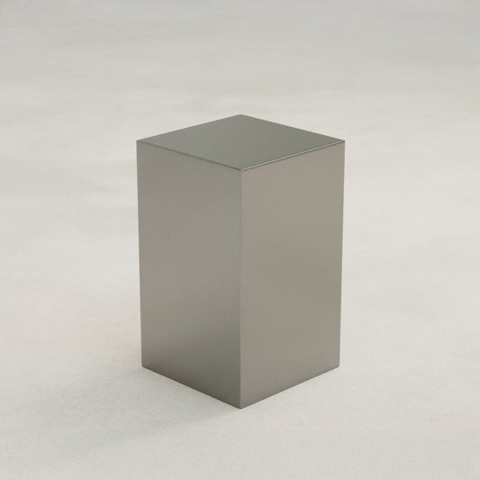 The Forge Steel Tall Plinth stands upright with smooth, rectangular steel surfaces on a light, neutral background, bringing modern style and industrial flair.
