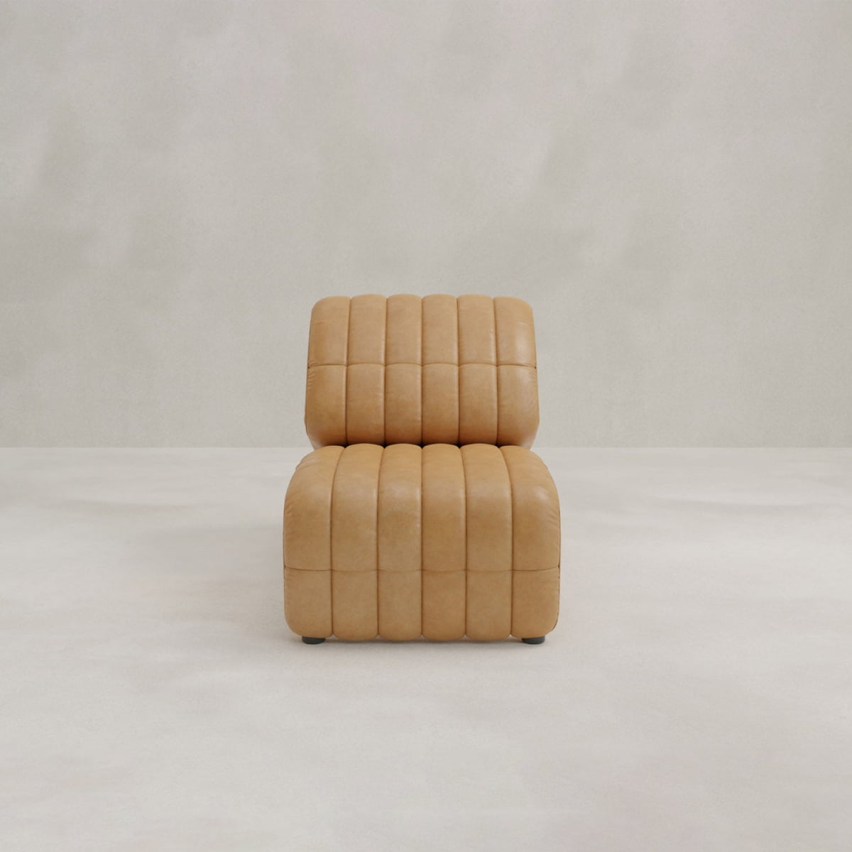A modern Hillier Chair, armless and upholstered in premium vintage tan leather with vertical tufted lines, sits on a light floor against an off-white background.