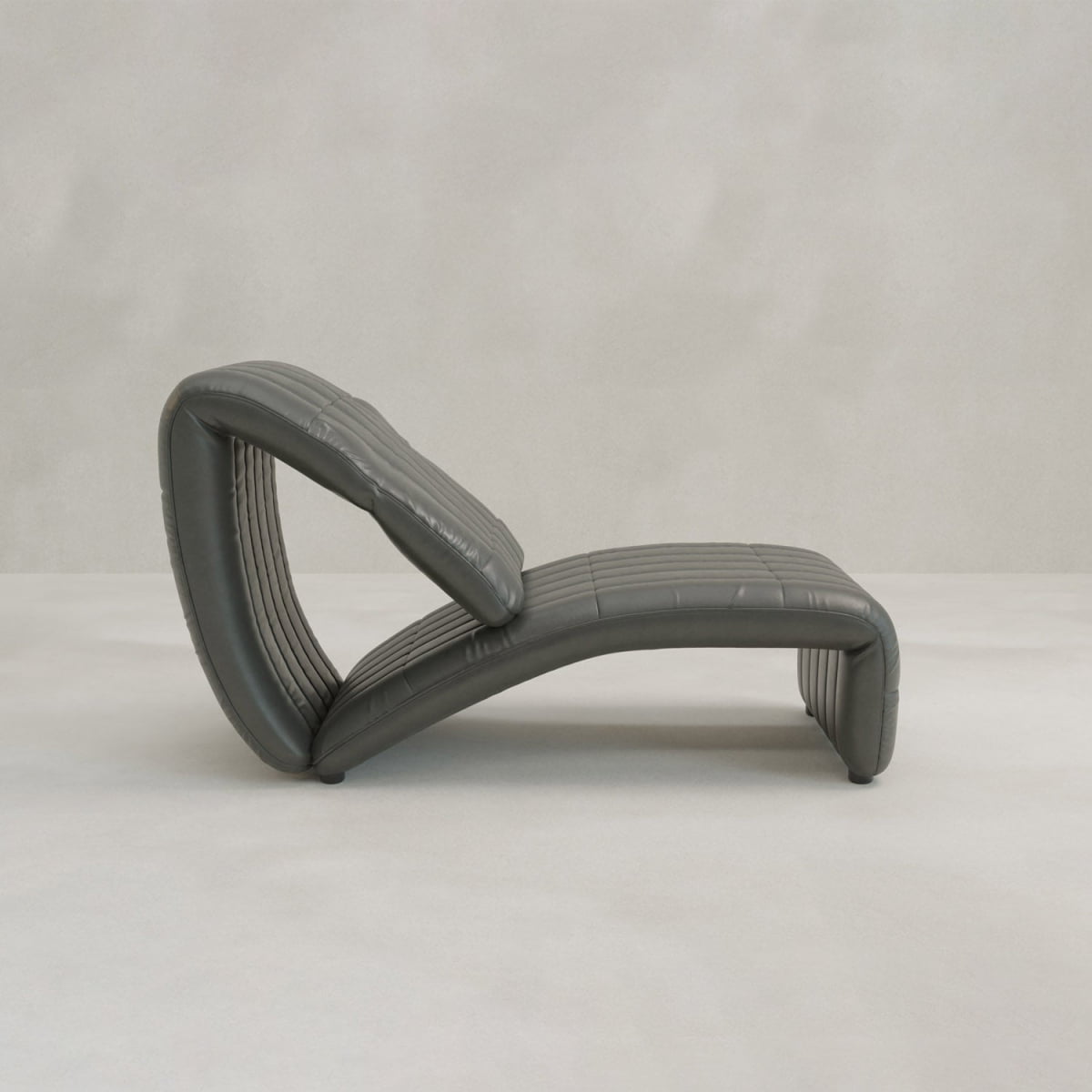 The Hillier Chair, made from premium vintage leather, boasts a modern curved design with reclining features. It’s displayed on a light floor with a plain, light grey background.