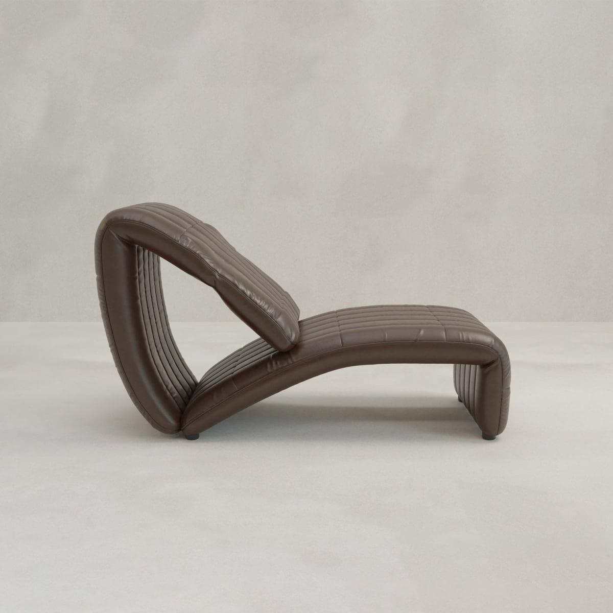 The Hillier Chair, crafted in premium vintage leather, features a contoured wave-like shape and elegant reclining design, shown in brown on a light floor with a neutral textured background.